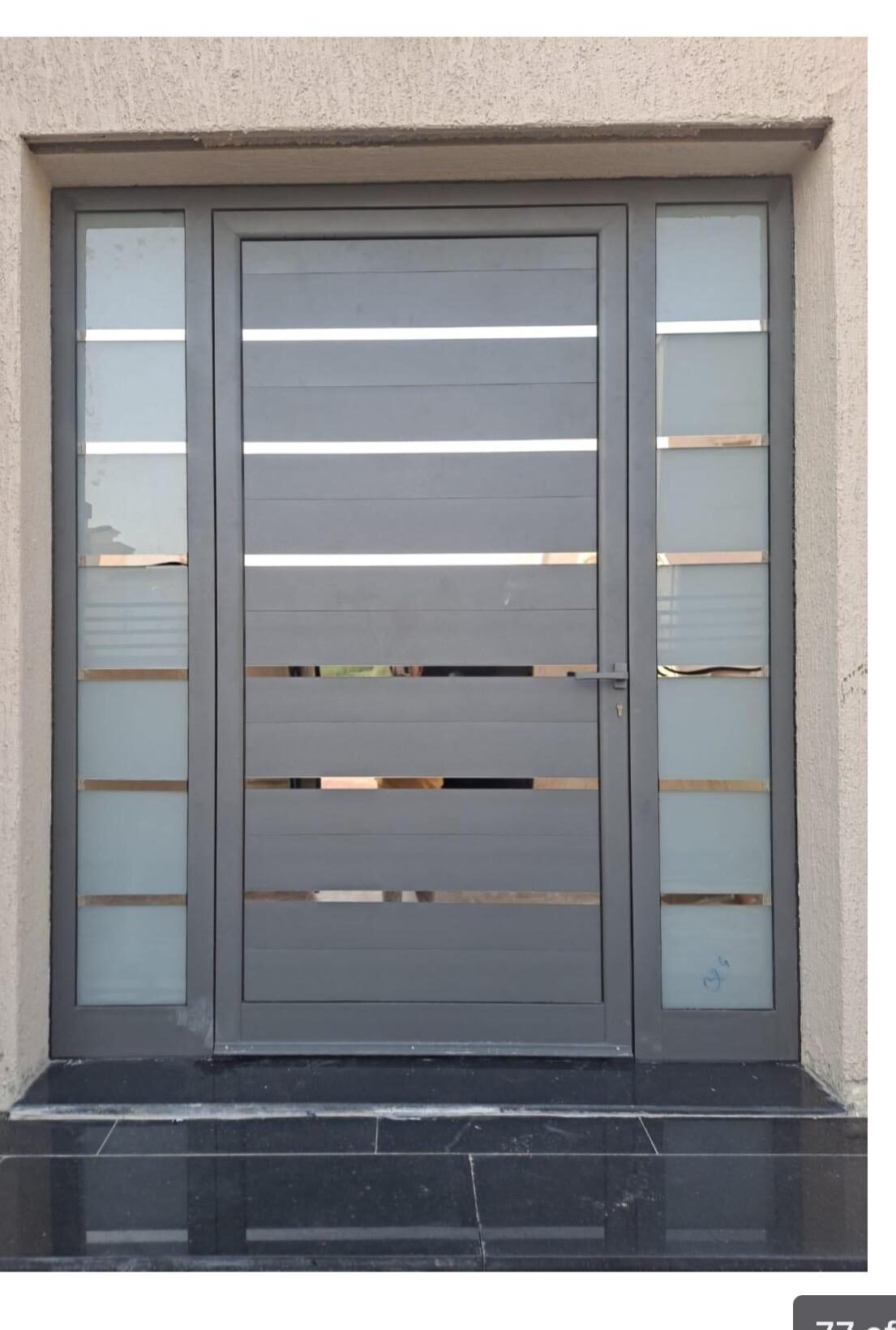 Grey aluminium door with horizontal slats on marble entrance